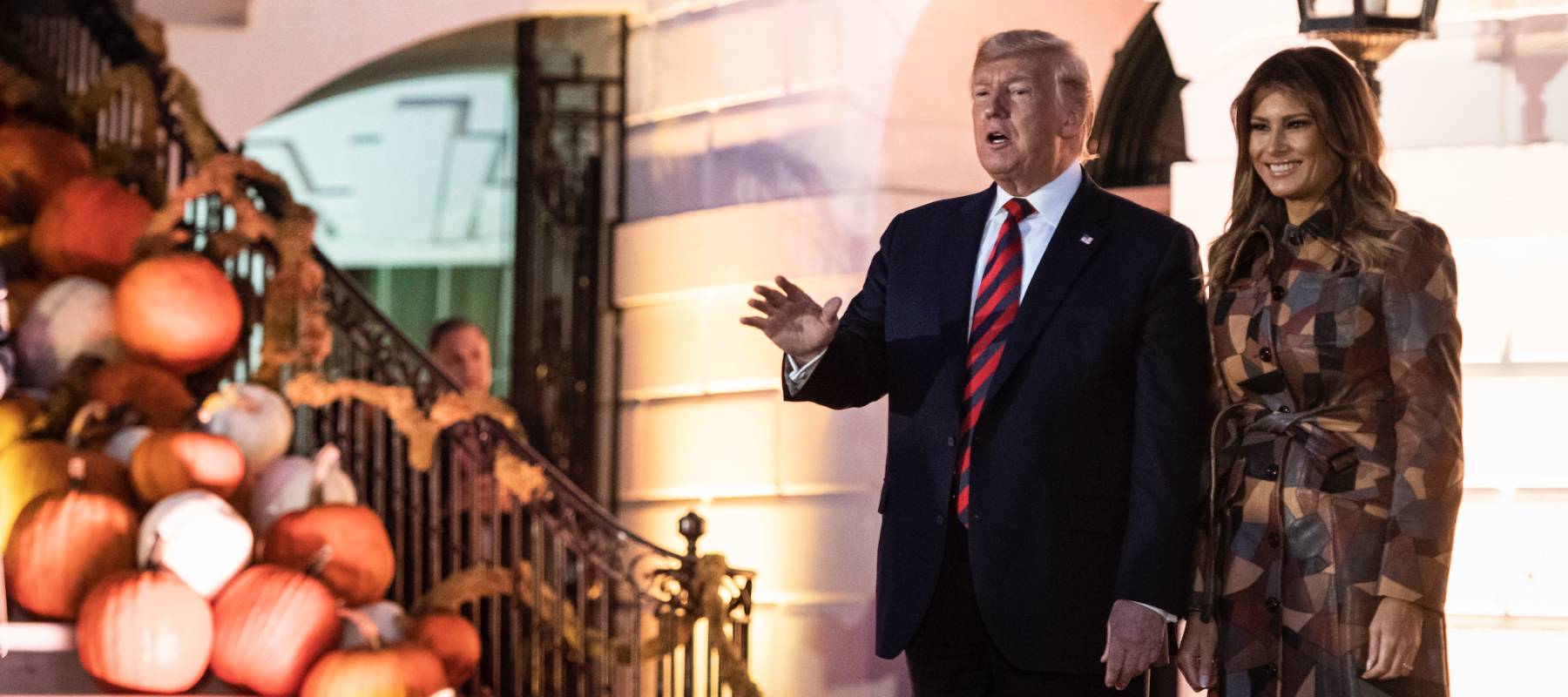 trump at trick or treat event with melania and staircase covered in pumpkins