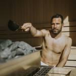 Man pouring water onto hot stone in the sauna.