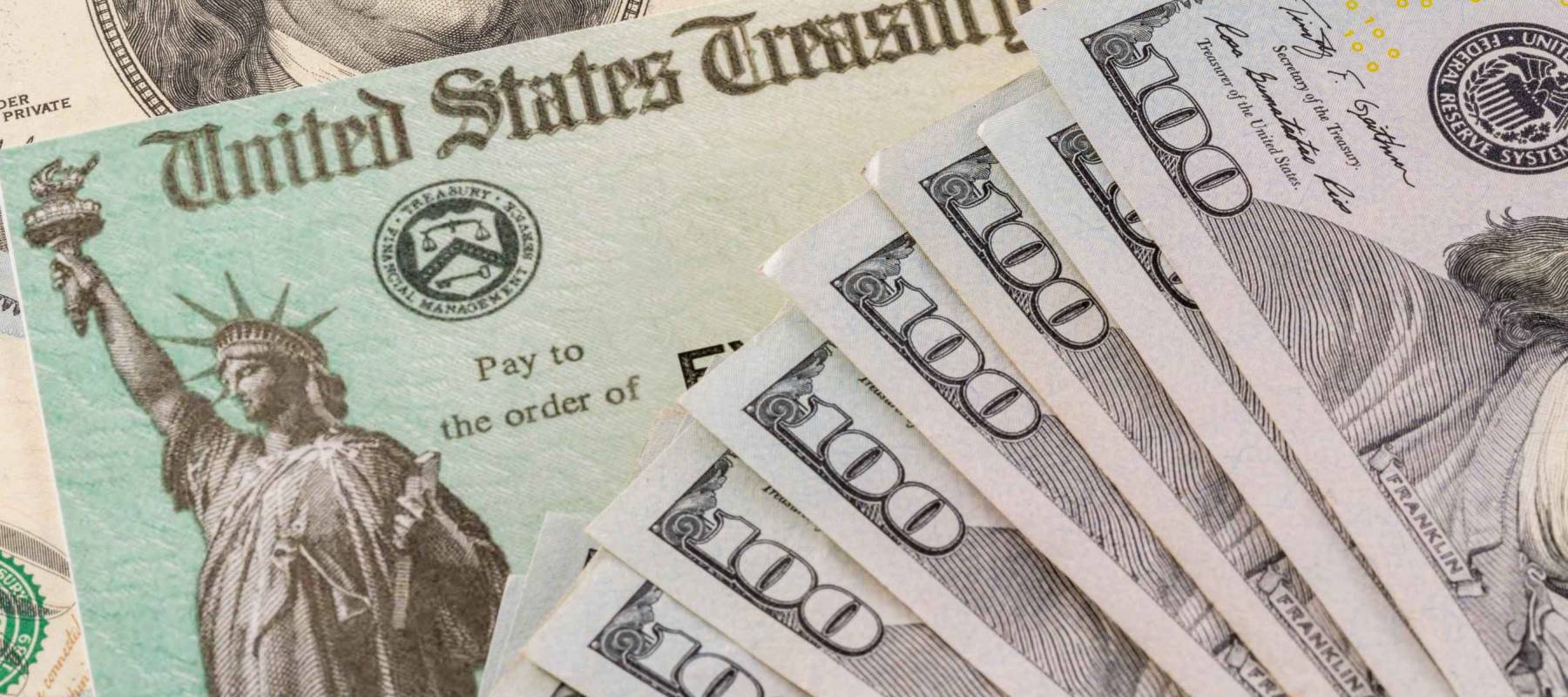 Stack of 100 dollar bills with illustrative coronavirus stimulus payment check to show the virus stimulus payment to Americans