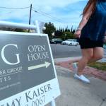 A woman walking past an open house sign.