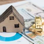 Model house, gold bars and cash, representing assets