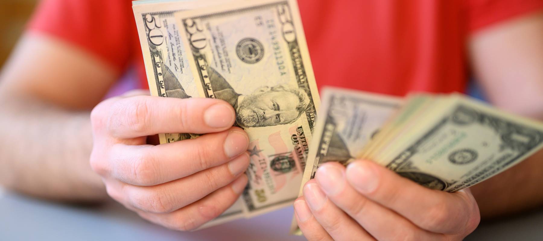 Man wearing red shirt counts out money