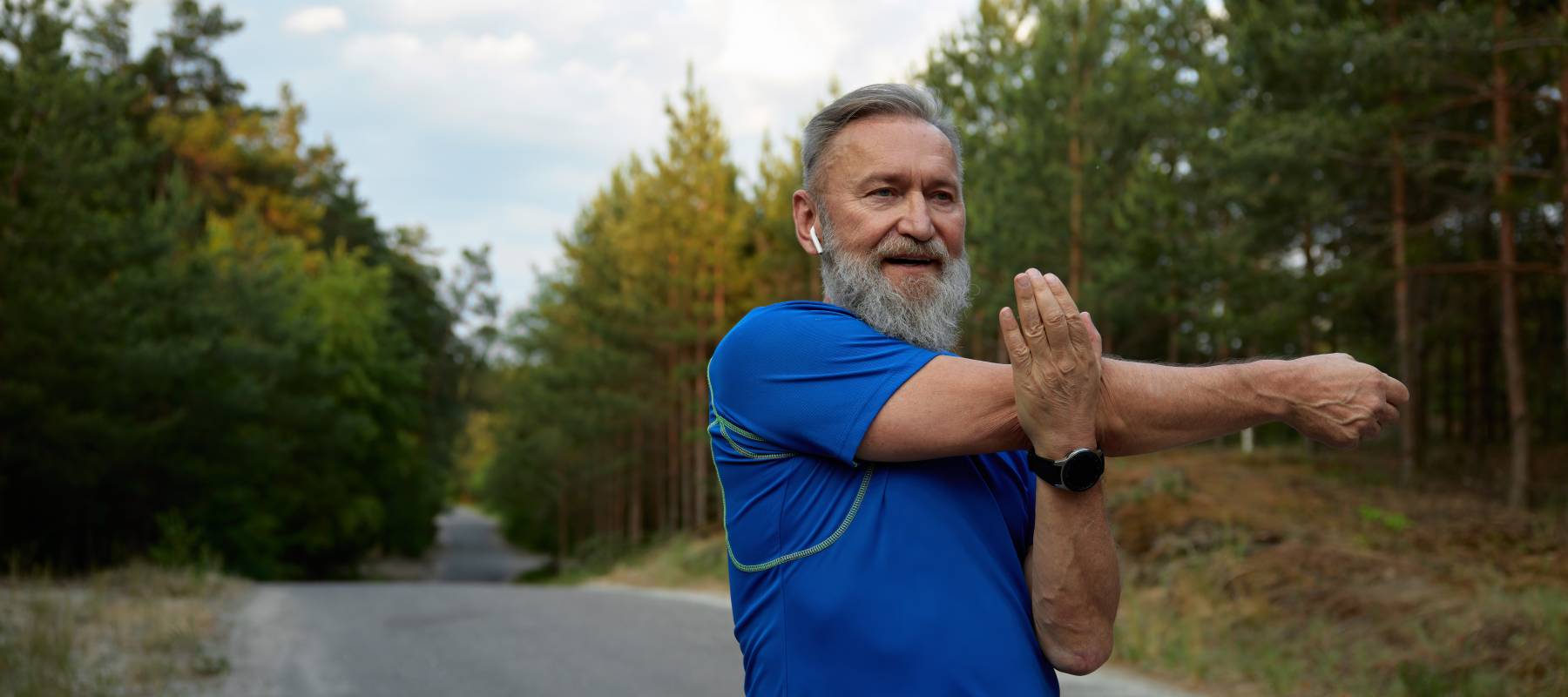 Happy retired Caucasian man stretching arms before running race start