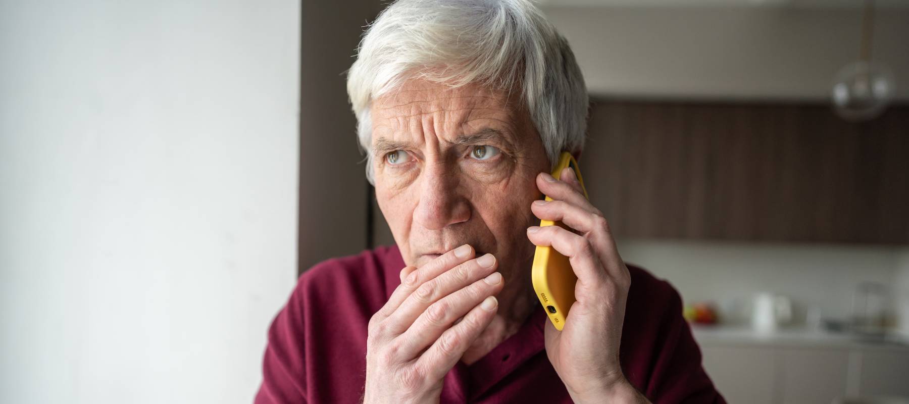 Suspicious elderly man with phone at home.