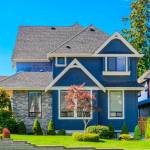 dark blue house with grey roof, white finishing against blue sky