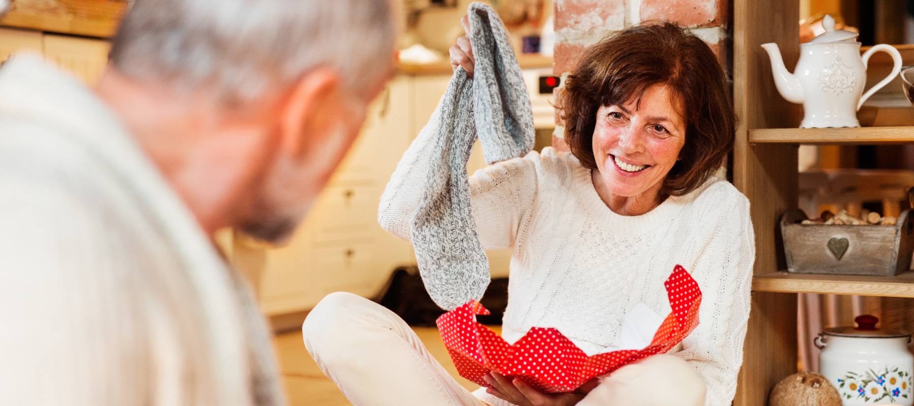 A woman opens.a Christmas gift to reveal a pair of socks, maybe signaling a tightening of holiday spending.