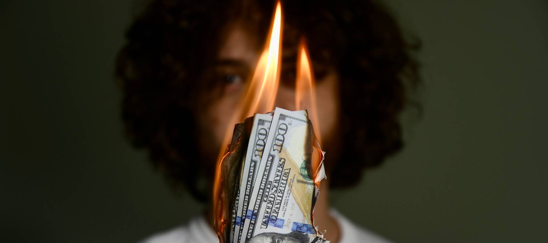 A person holding burning cash.