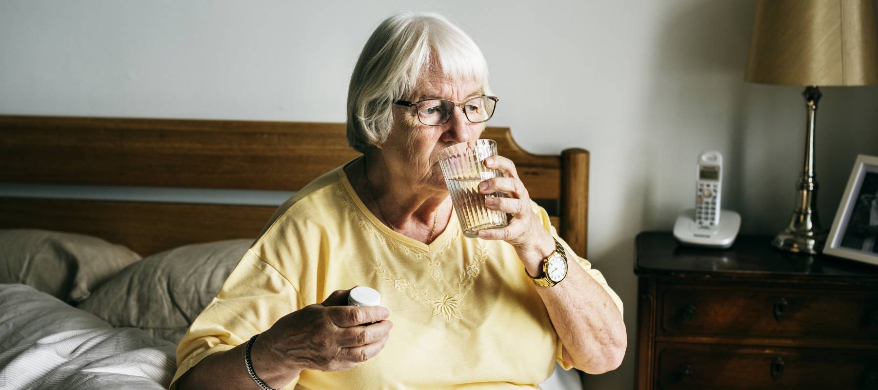 Senior woman having pills on her bed.