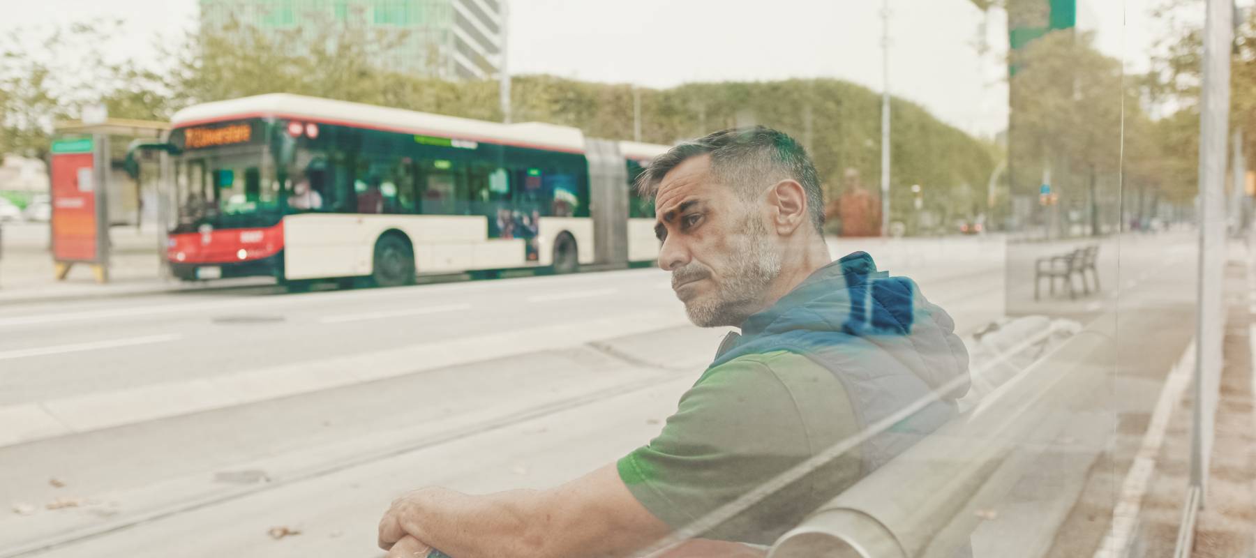middle-aged Caucasian man with backpack on his shoulder, looks around at public transport stop