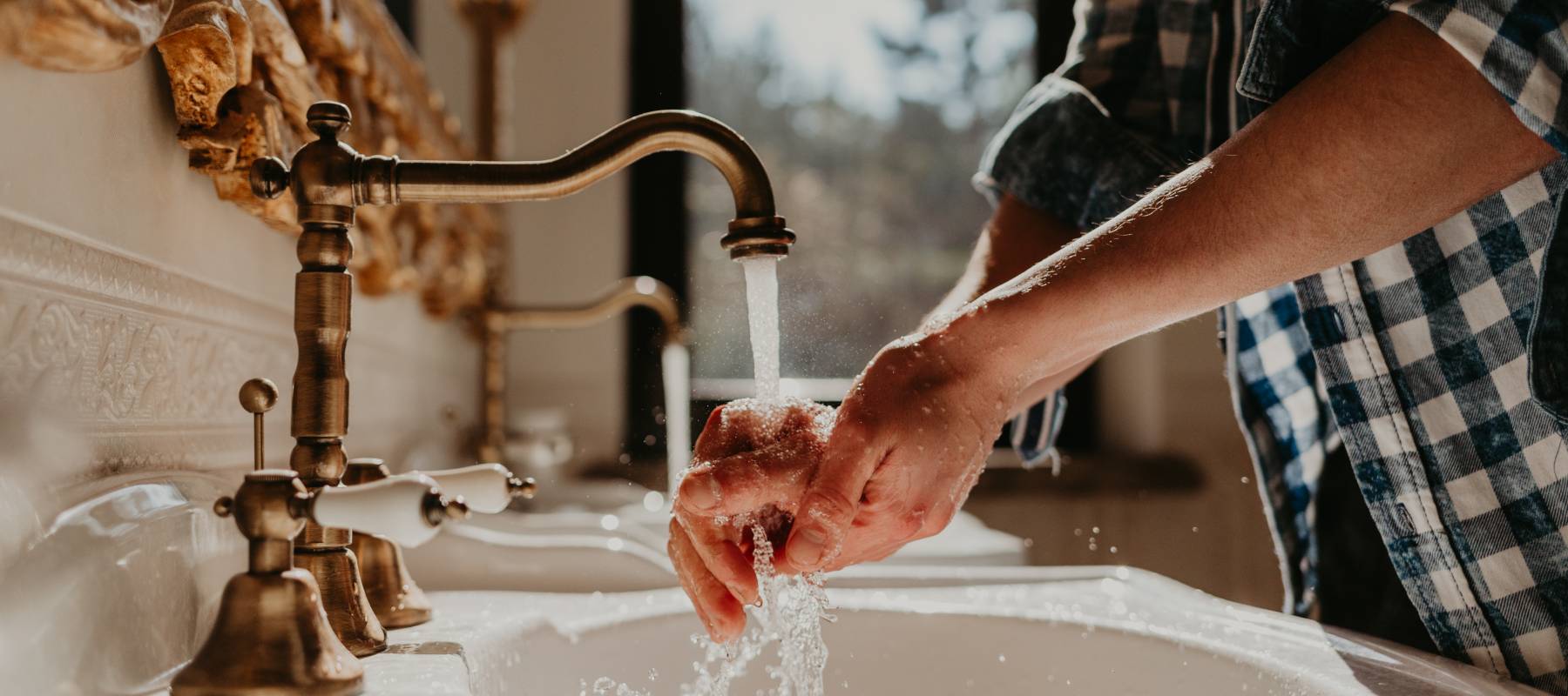 Close up of man washing hands in sink.