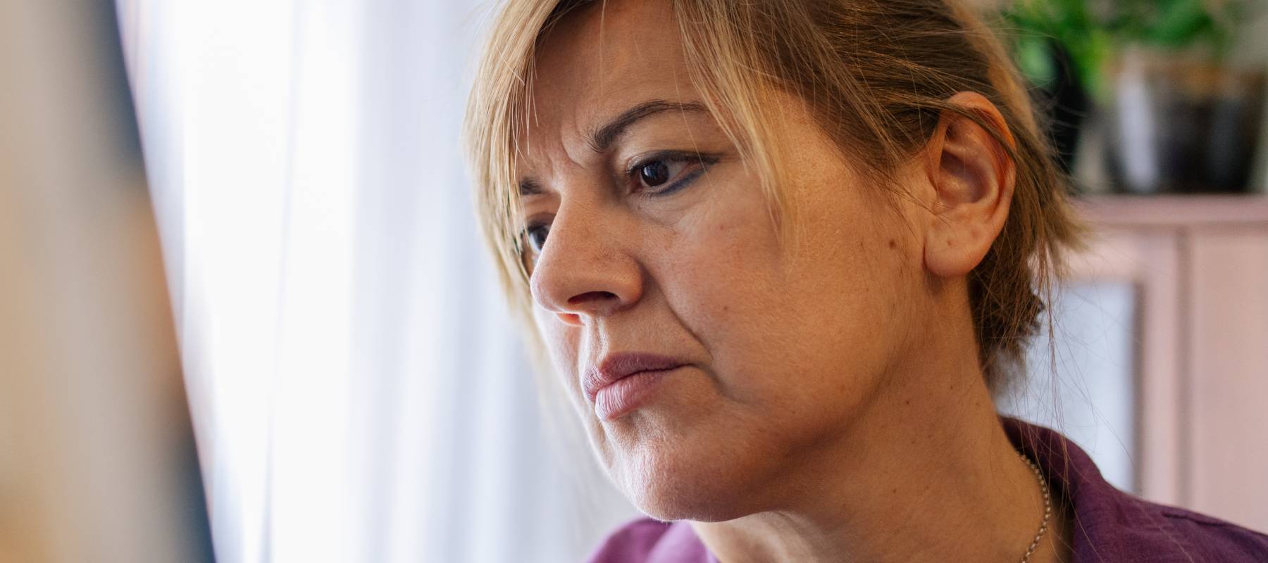 An older woman looking at a canvas.