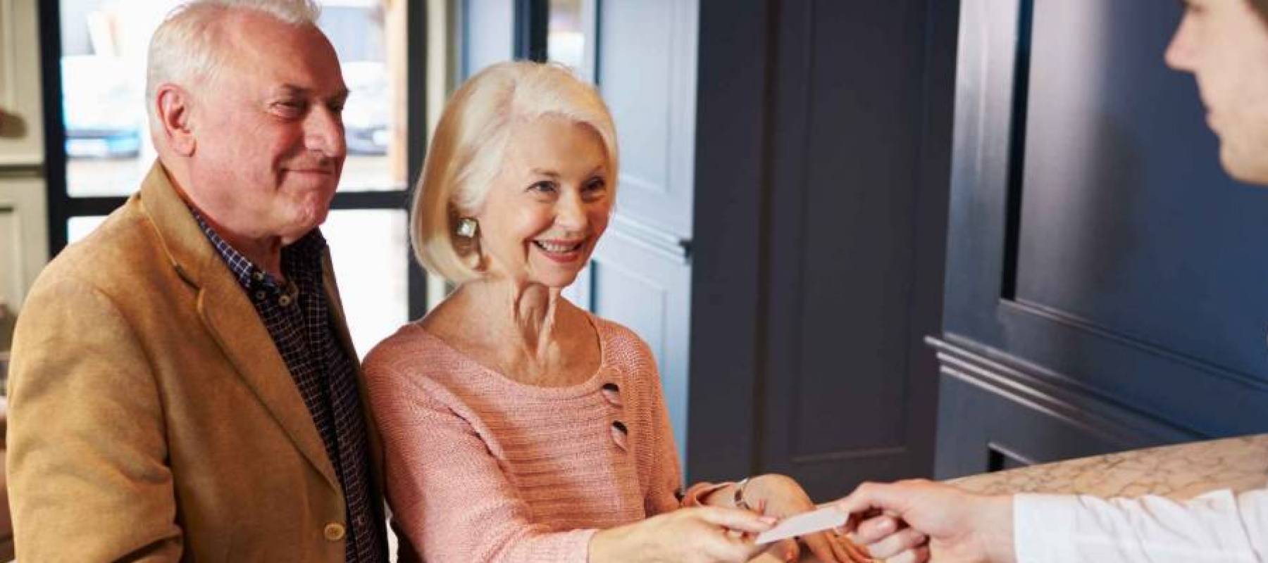 Senior Couple Checking In At Hotel Reception