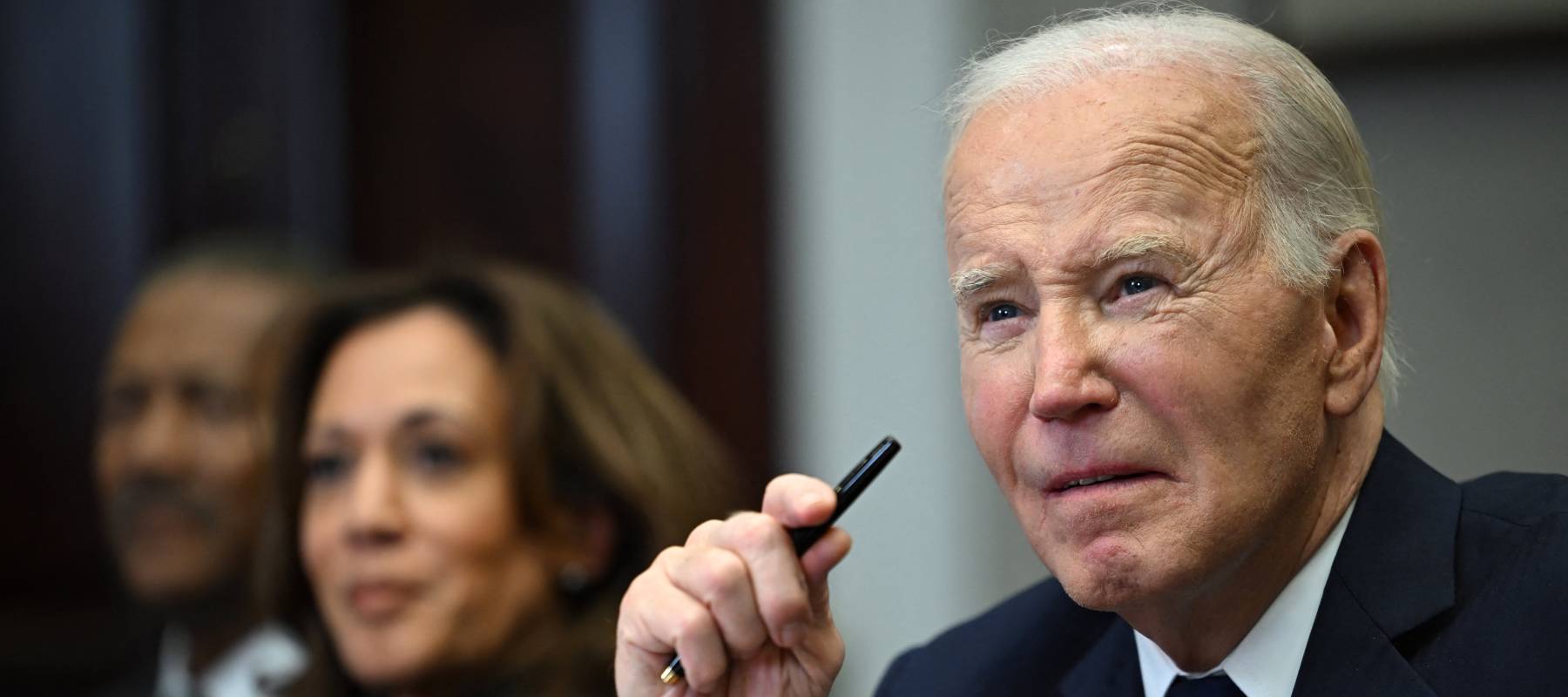 Go Biden holds up a pen at an early 2024 Los Angeles fires press event with Kamala Harris.