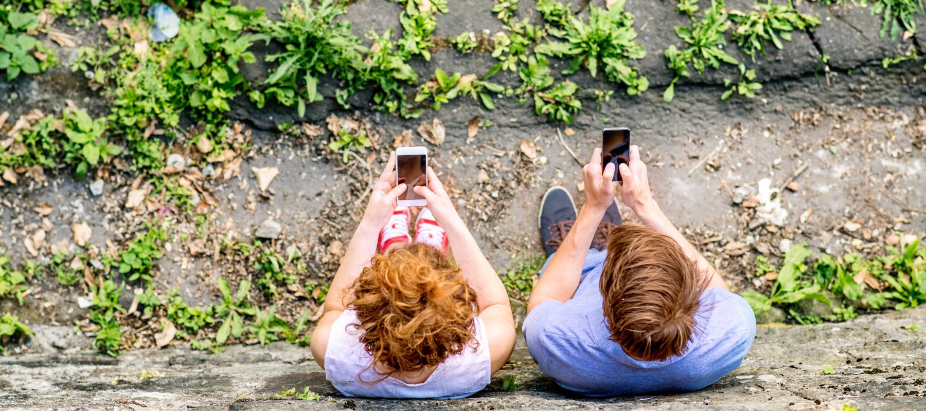 A couple stand side by side on their smartphones.