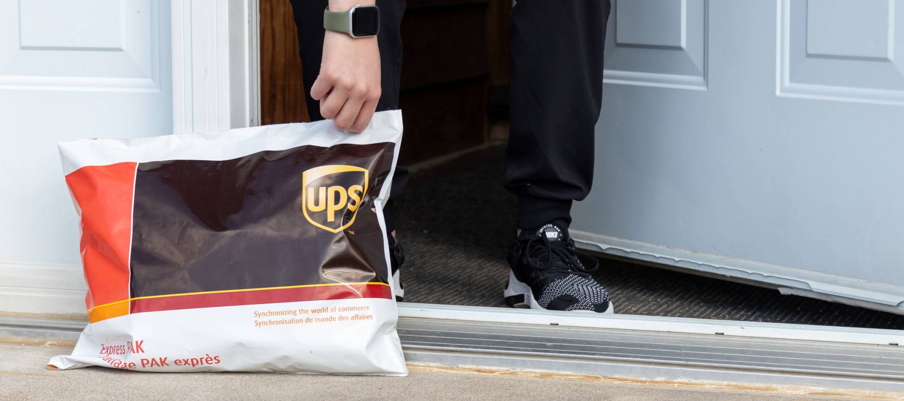 Person picking up a UPS package left at their front door.