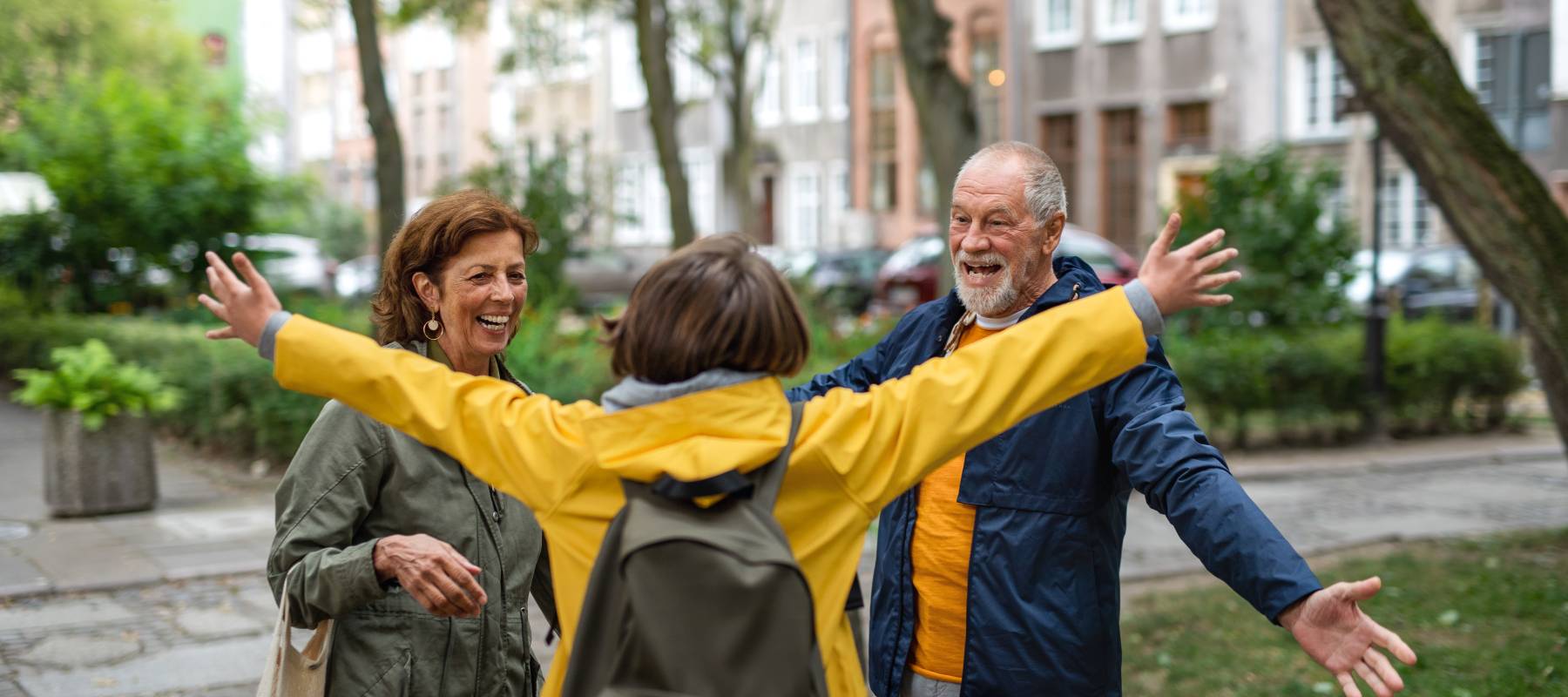 two older Caucasians greeting a young woman at university