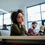 Black woman falling asleep at her desk in a work office environment