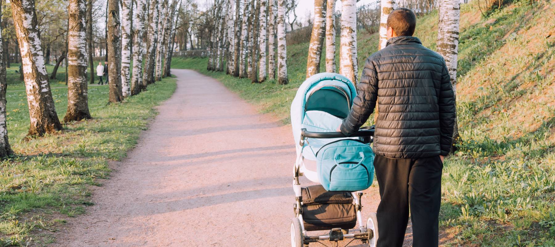 A man walking his new baby on a park trail.