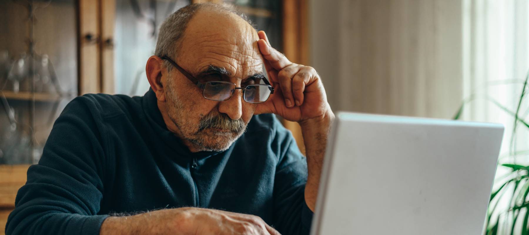 An older man sits on a computer at a restaurant after hours.