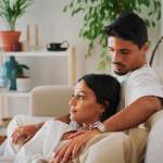 married Middle Eastern couple relaxing on the couch, serious expressions