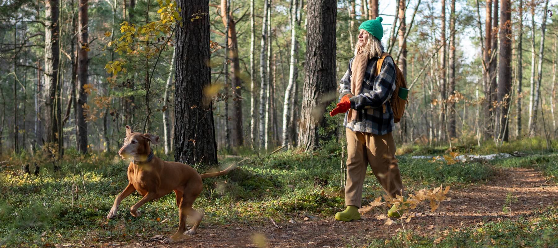 A woman in the woods with her dog.