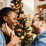 Happy and loiving woman and man next to a Christmas tree on Christmas morning