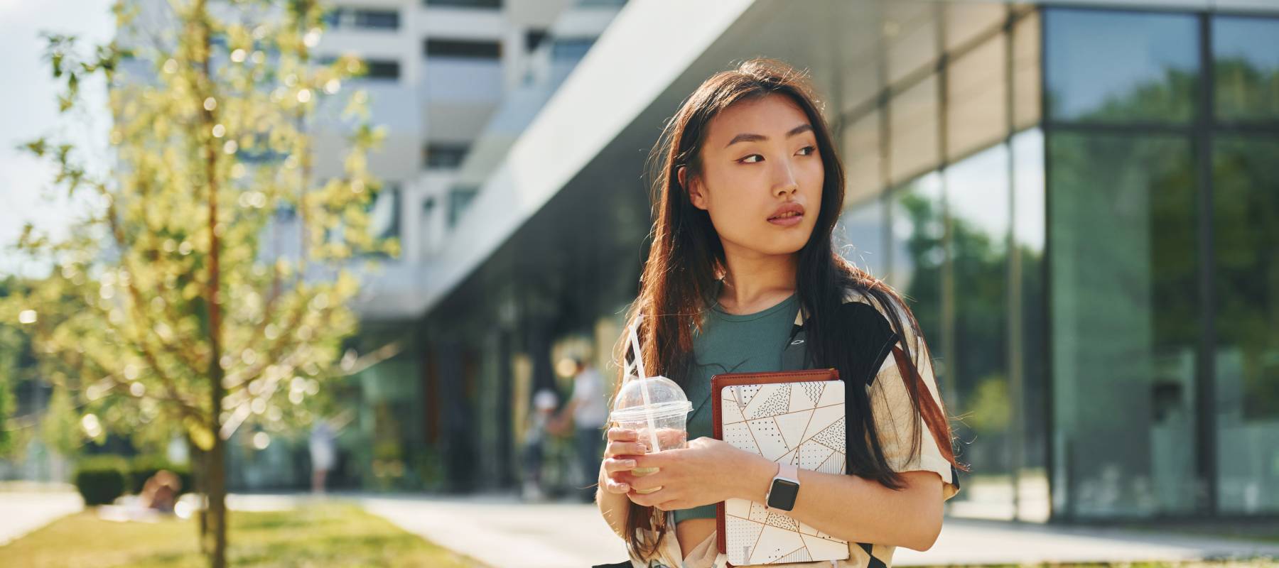 young Asian woman is outdoors at school campus