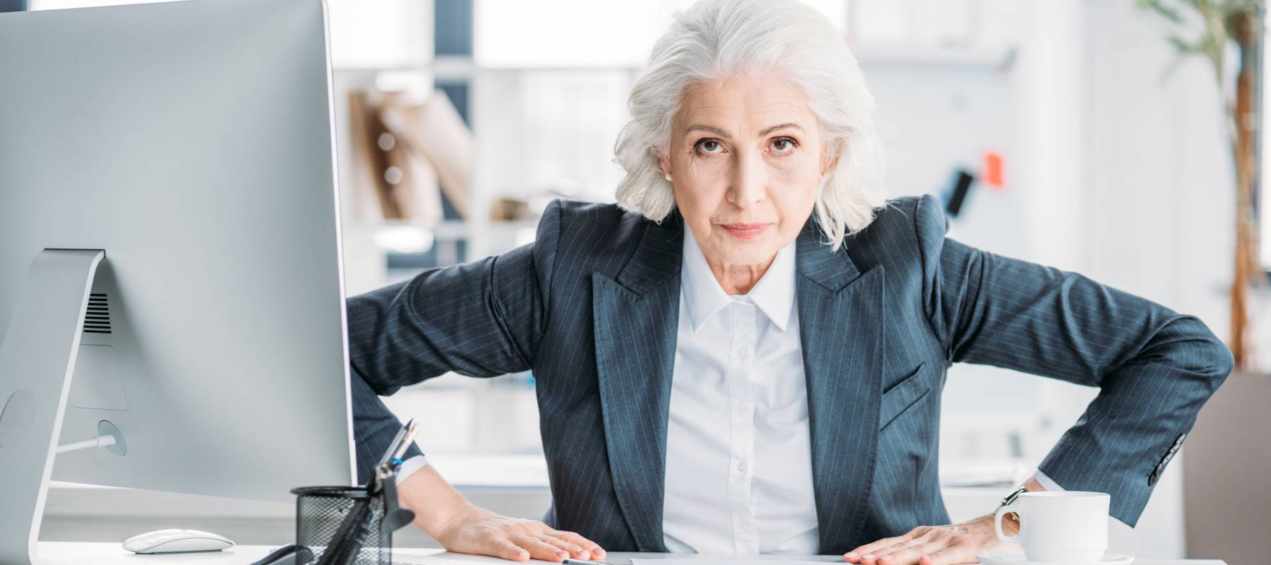 a Caucasian senior woman aggressively looking at the camera while at a corporate office