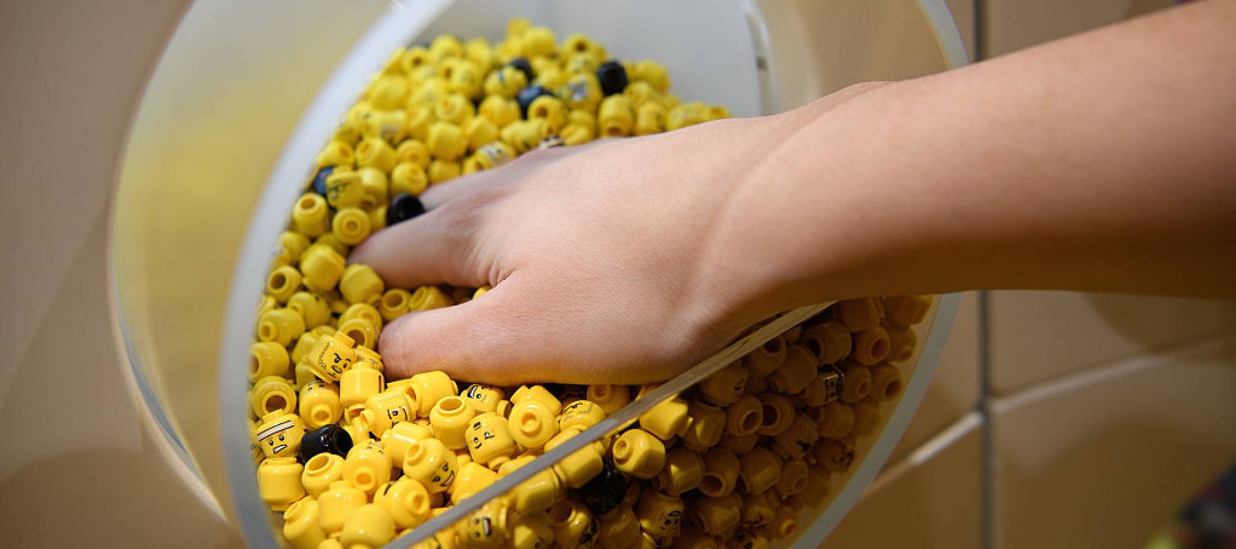 A sales assistant holds a handful of Lego figure heads