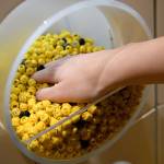 A sales assistant holds a handful of Lego figure heads