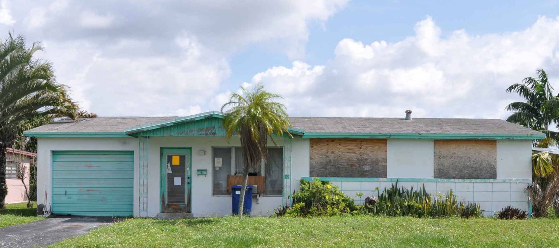 Boarded up Suburban Ranch home blue sky clouds USA