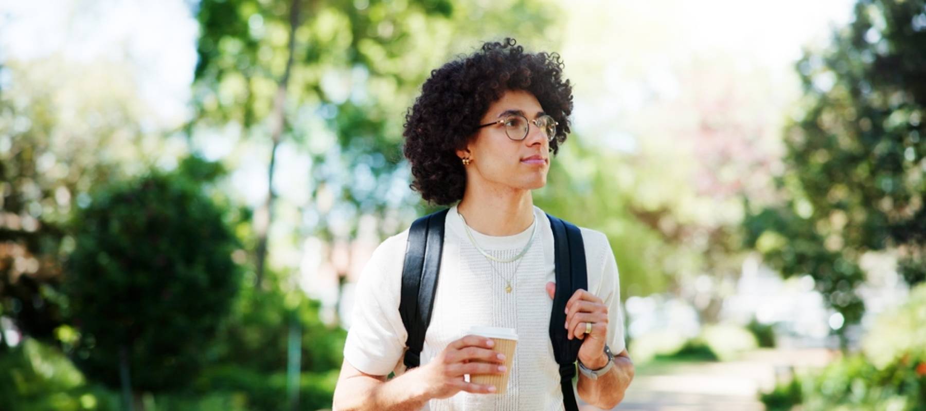 man on campus with coffee, backpack and glasses on morning commute to college