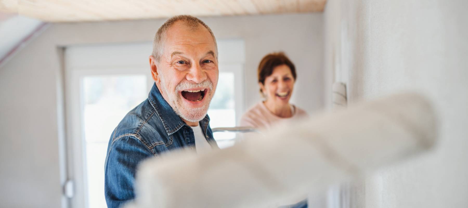 a Caucasian senior couple painting a bedroom
