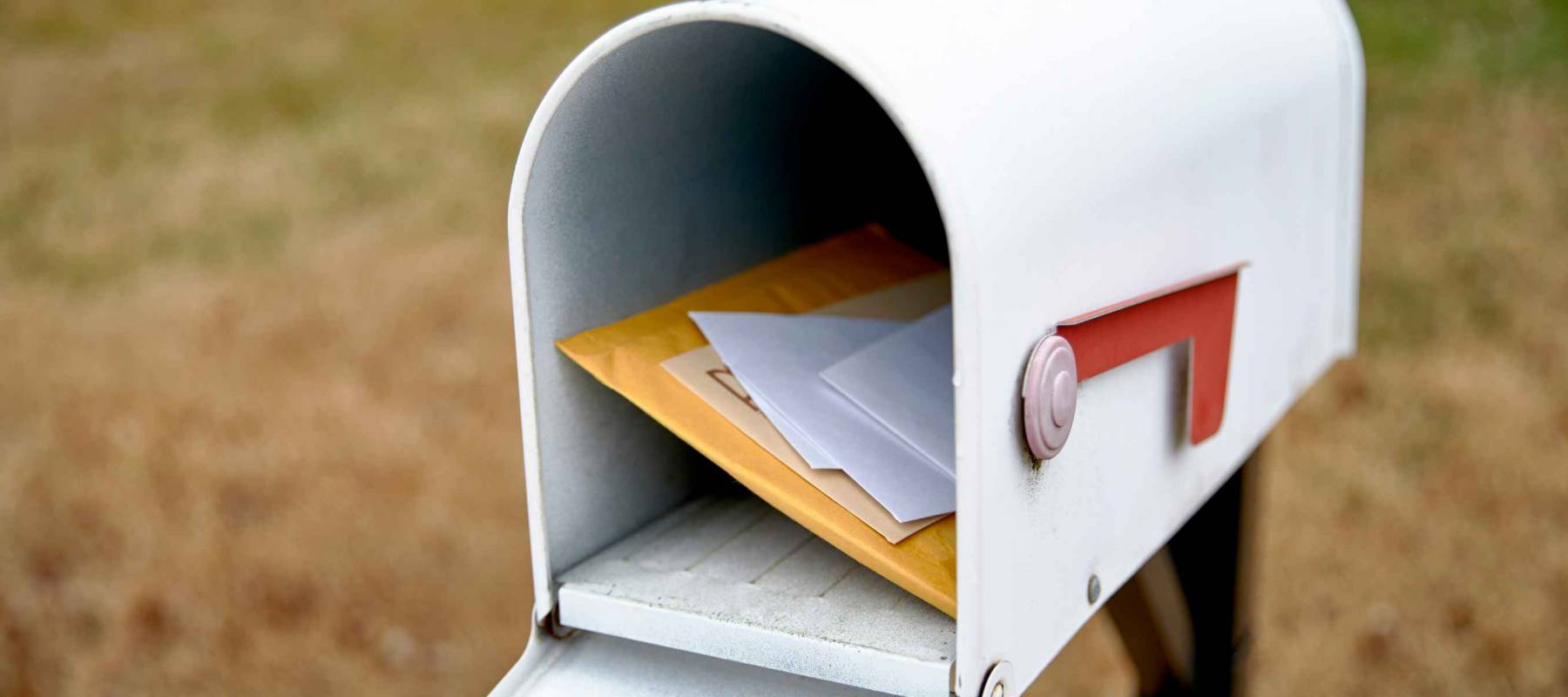 Close up of a mailbox opened with the contents of the mailbox showing with shallow depth of field