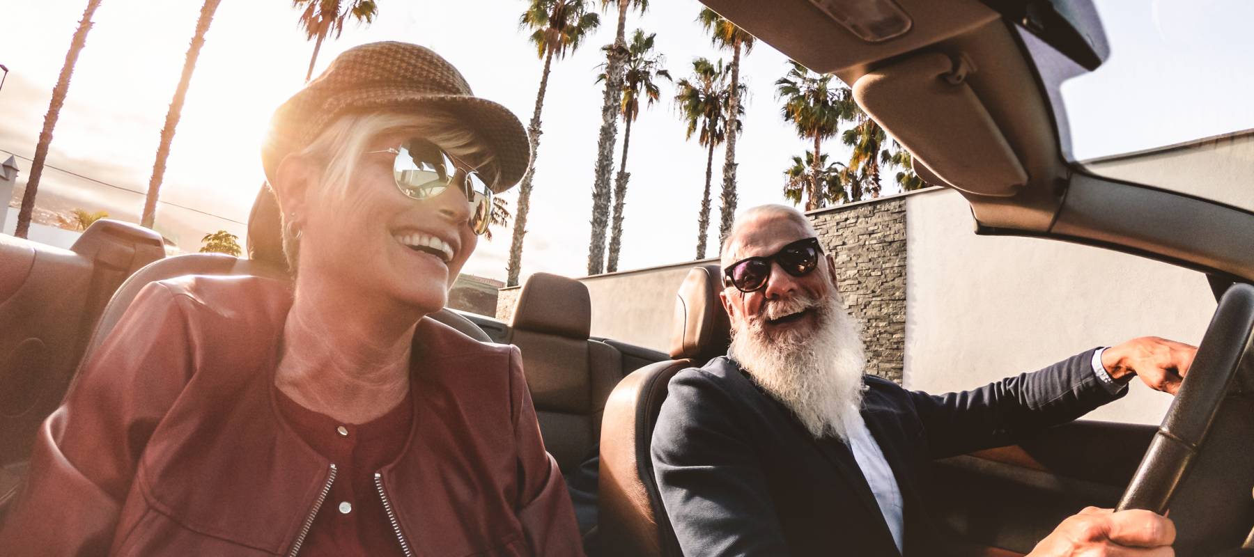 trendy Caucasian senior couple smiling in an expensive car