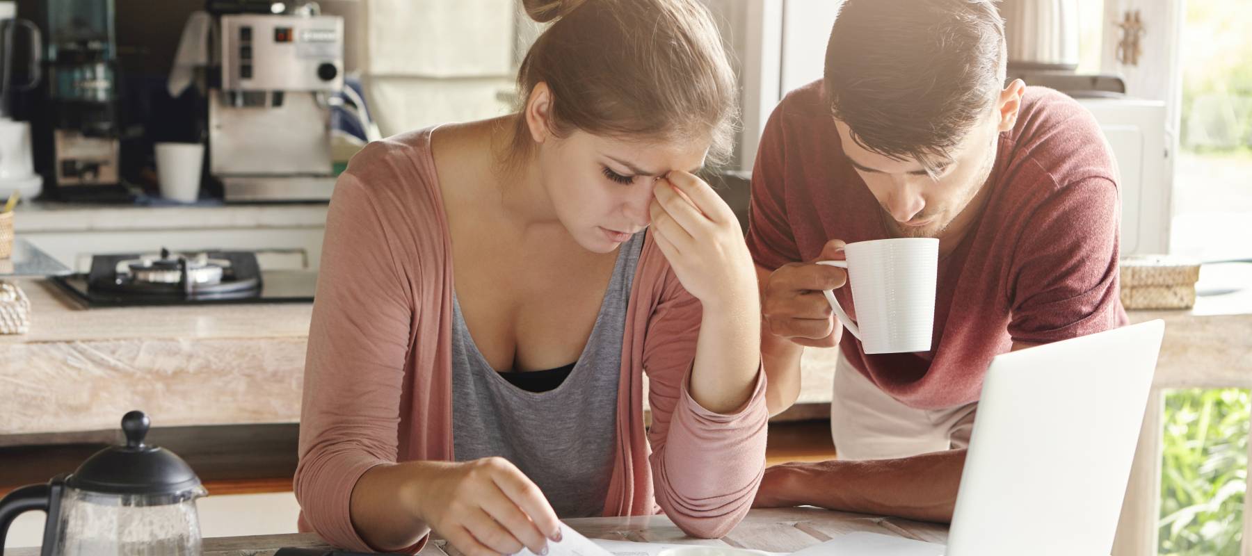 young Caucasian couple at home, looking a little stressed, while surrounded by finance paperwork in their kitchen
