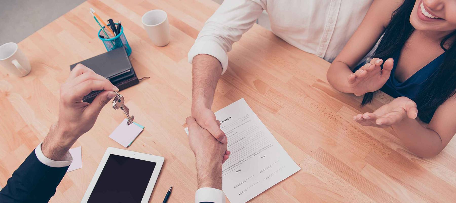 Broker giving keys of new house and handshaking with customer