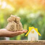 Man holding money bag and home model