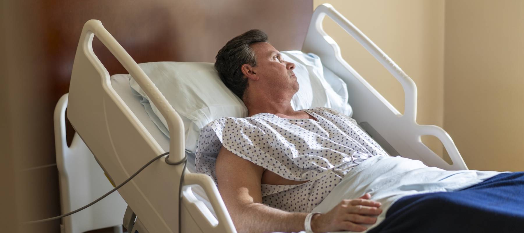 Man resting in a hospital bed looking out the window