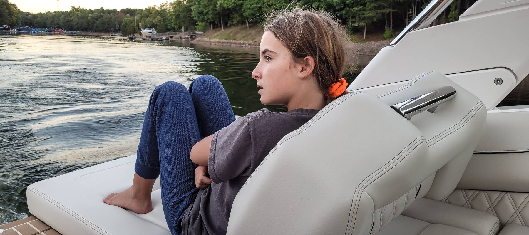 Gen Z woman looks disappointed while sitting on a nice boat.
