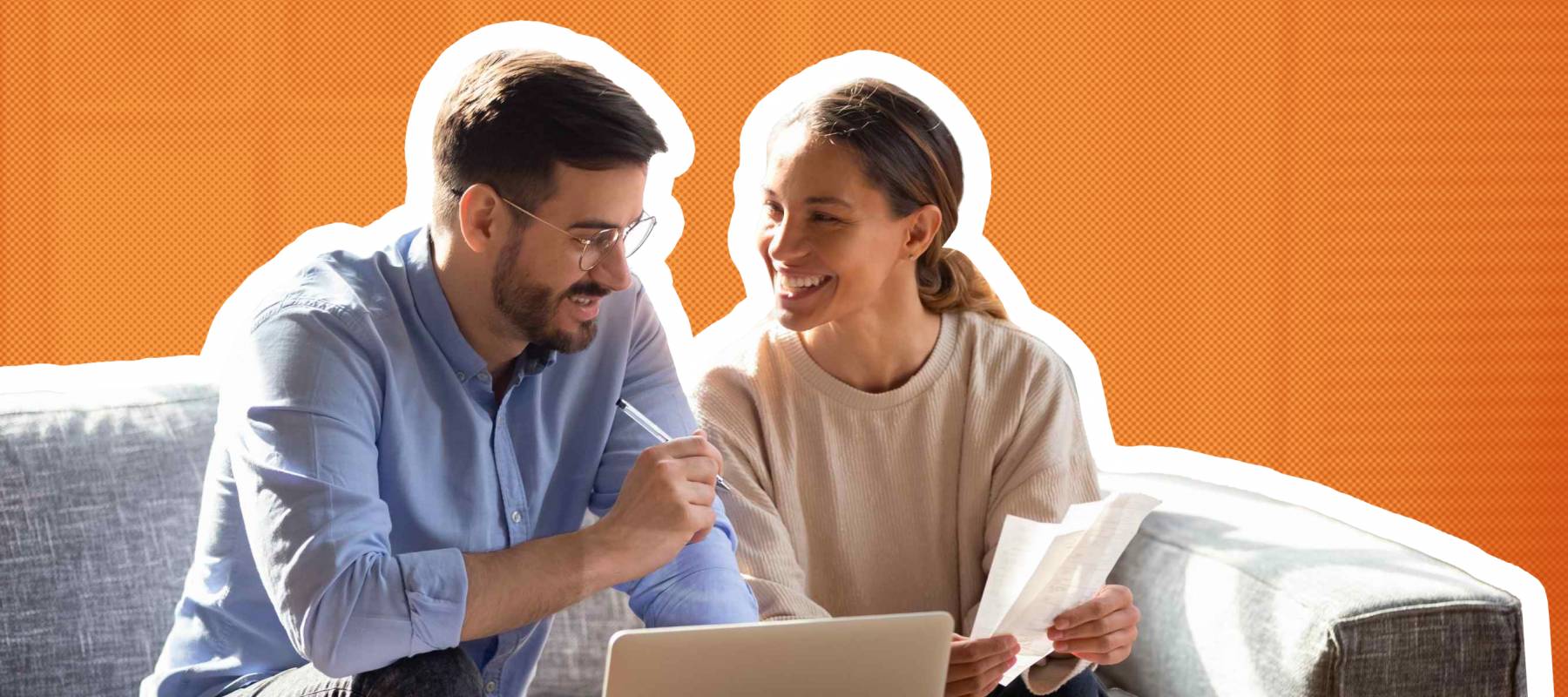 smiling young couple on couch with papers and open laptop