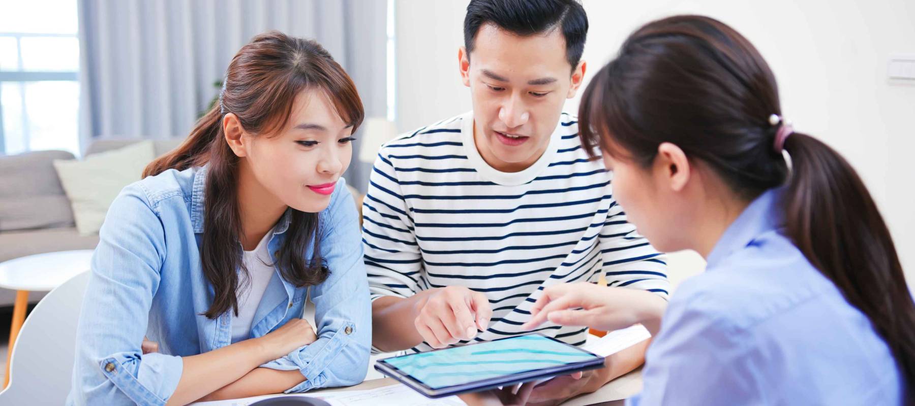 Young asian couple looking house with real estate agent by tablet pc