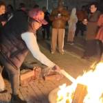 A crowd of North Lawndale residents gather around a roaring fire on a hardscaped patio to burn their property tax bills.