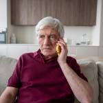serious senior man show distrust during phone conversation at home, fraud attempt concern