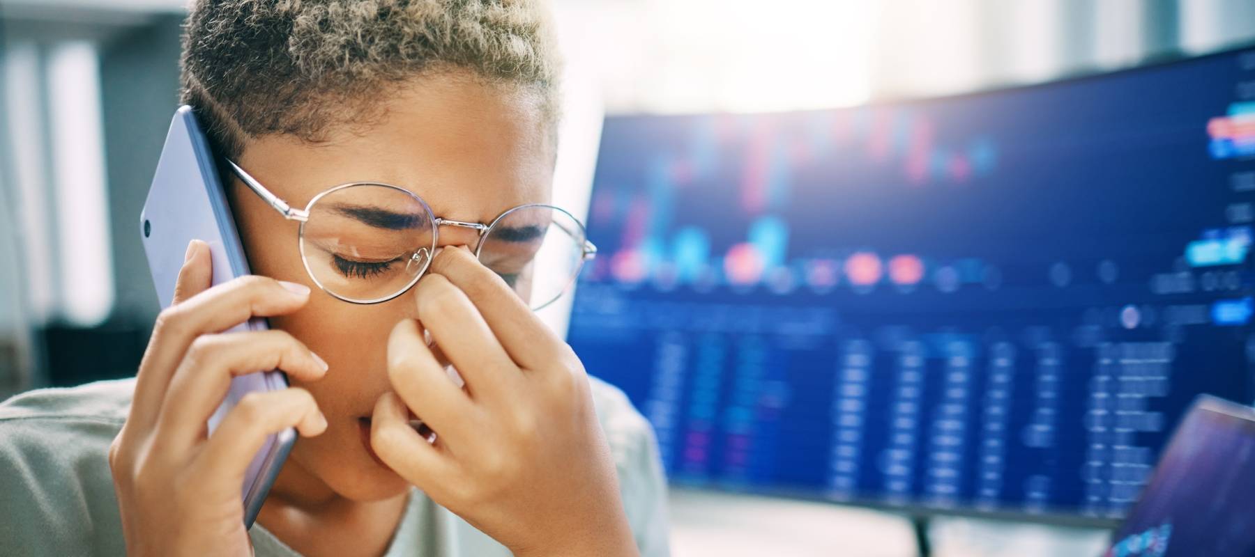a young Black woman at her office desk looking stressed about stock market crash