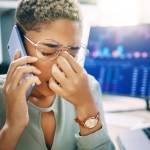 a young Black woman at her office desk looking stressed about stock market crash