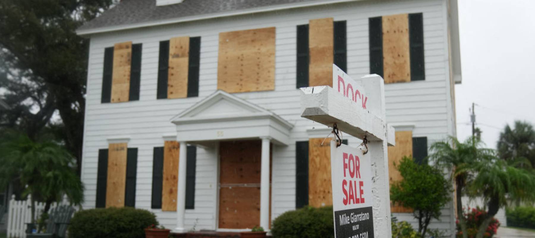 House for sale with boarded up windows.