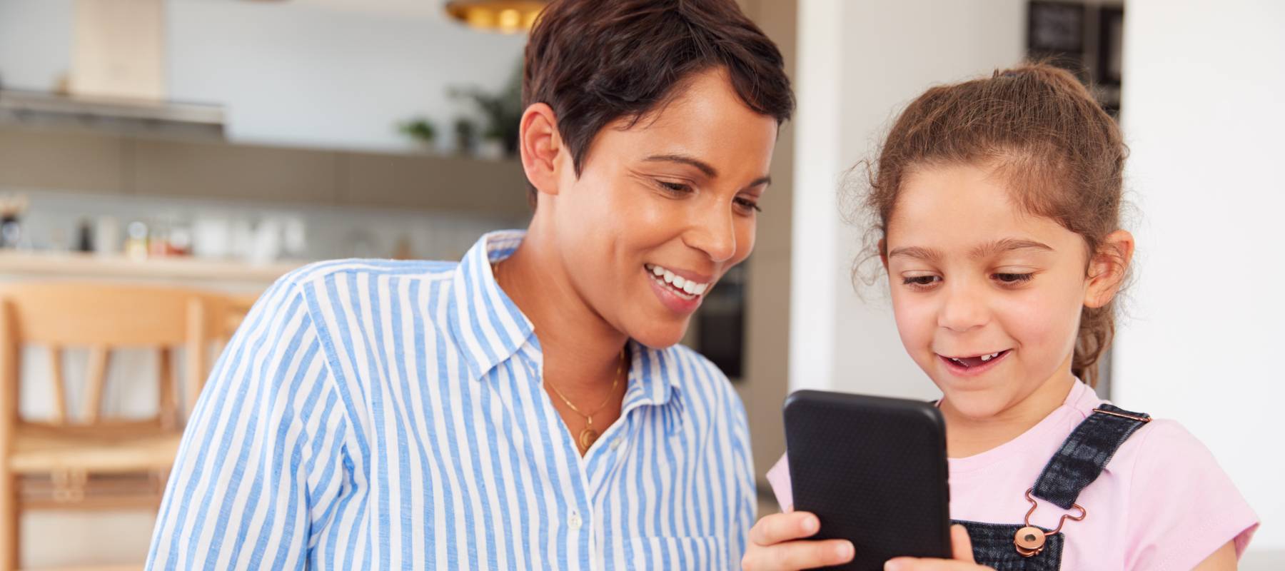 mother And daughter looking at mobile phone together at home