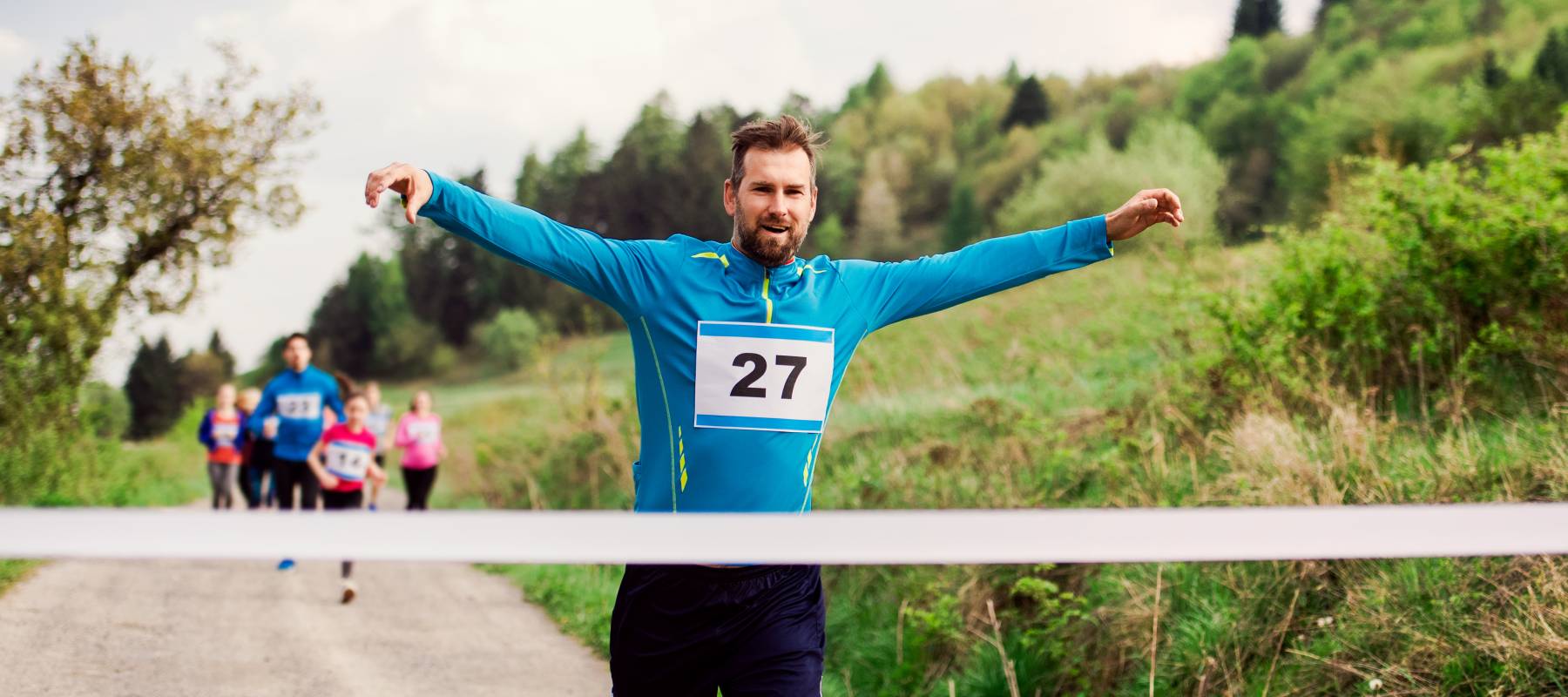Caucasian man in his mid- to late-40s crossing the finish line at a marathon