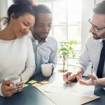 happy couple hold coffee cups and look at paper as man explains something to them